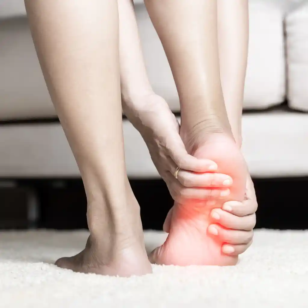 Person holding a painful heel and arch